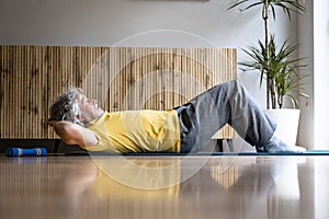 Senior man in yellow shirt working out practicing a pilates exercise