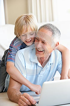 Senior man with young boy using laptop computer