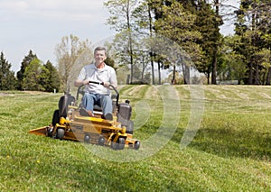 Senior man on zero turn lawn mower on turf