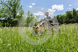 Senior man on zero turn lawnmower in meadow