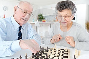 Senior married couple playing chess at home