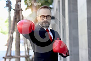 Senior mature businessman wearing red boxing gloves or mitt punch, metaphors about fight business for successful, elderly man