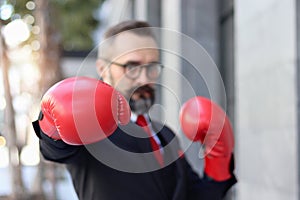 Senior mature businessman wearing red boxing gloves or mitt punch, metaphors about fight business for successful, elderly man