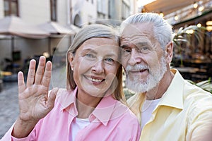 Senior mature family couple gray-haired people man and woman smiling and looking at camera talking on video call looking