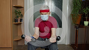 Senior mature grandfather man in sportswear doing weightlifting dumbbell exercising at home