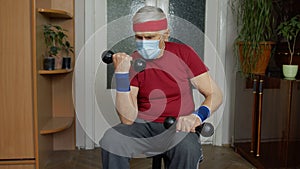 Senior mature grandfather man in sportswear doing weightlifting dumbbell exercising at home