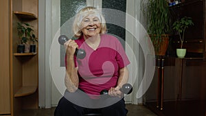 Senior mature grandmother woman doing weightlifting training workout dumbbell exercising at home