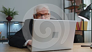 Senior mature older business man hiding behind laptop computer, making funny face, fooling around