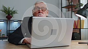 Senior mature older business man hiding behind laptop computer, making funny face, fooling around