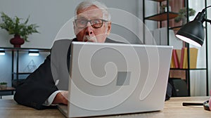 Senior mature older business man hiding behind laptop computer, making funny face, fooling around