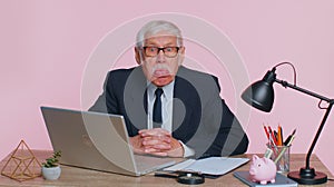Senior mature older office businessman working on laptop computer, making funny face, fooling around