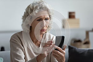 Senior mature retired woman reading unpleasant news in social media.