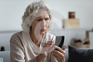Senior mature retired woman reading unpleasant news in social media. photo