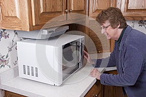 Senior Mature Woman Cooking Microwave Oven Kitchen