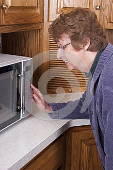 Senior Mature Woman Cooking Microwave Oven Kitchen