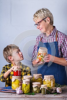 Senior mature woman with grandson holding in hands preserved food