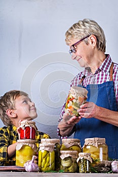 Senior mature woman with grandson holding in hands preserved food