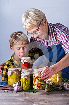 Senior mature woman with grandson holding in hands preserved food