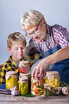 Senior mature woman with grandson holding in hands preserved food