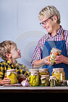 Senior mature woman with grandson holding in hands preserved food