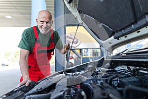 Senior mechanic checking the oil level in the car engine.