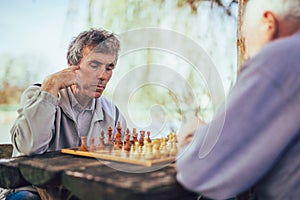 Senior men having fun and playing chess at park