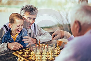 Senior men having fun and playing chess at park