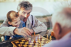 Senior men having fun and playing chess at park