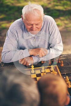 Senior men having fun and playing chess at park