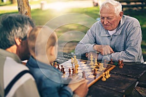 Senior men having fun and playing chess at park