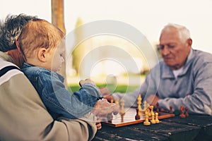 Senior men having fun and playing chess at park