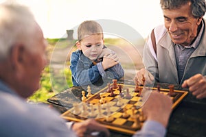 Senior men having fun and playing chess at park