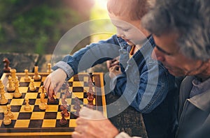 Senior men having fun and playing chess at park, spend time with grandson