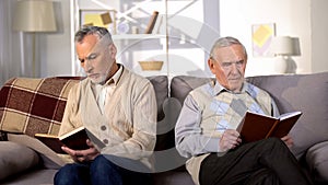 Senior men reading books in nursing home sitting sofa, retirement leisure, hobby