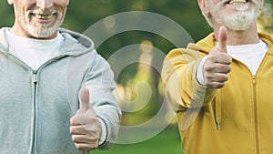 Senior men in sport suits showing thumbs-up, fitness club for pensioners, health