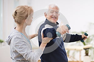 Senior after stroke at nursing home exercising with professional physiotherapist photo