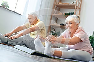 Senior couple doing yoga together at home health care legs stretching