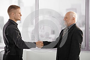 Senior and mid-adult businessman shaking hands