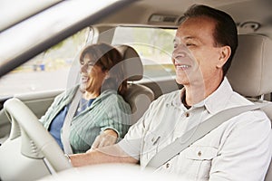 Senior mixed race couple sit smiling in car