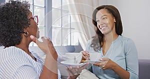 Senior mixed race woman drinking tea with her daughter in social distancing
