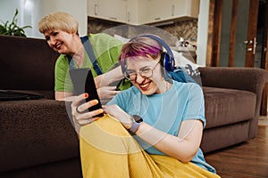 Senior mom and her adult daughter enjoying digital audiobook in living room