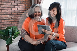 Senior mom and her adult daughter are using tablet