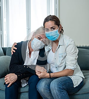 Senior mother and adult daughter crying at home worried about coronavirus