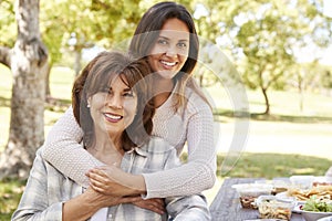 Senior mother and adult daughter embracing in park, close up