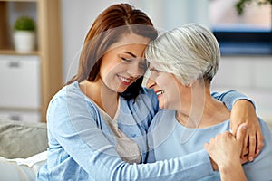 Senior mother with adult daughter hugging at home