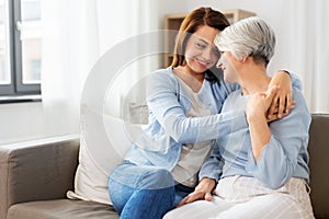 Senior mother with adult daughter hugging at home
