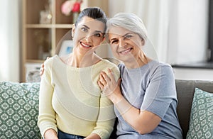 Senior mother with adult daughter hugging at home