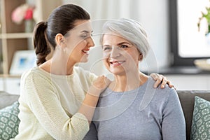 Senior mother with adult daughter hugging at home