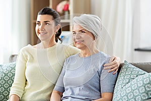 Senior mother with adult daughter hugging at home