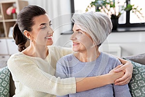 Senior mother with adult daughter hugging at home